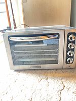 Front view of KitchenAid countertop oven showing glass door, handle and control knobs