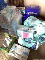 Stack of boxed facial tissues, paper towel pack, wipe pouch visible