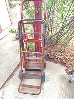 Front view of three nested steel hand trucks showing frames and wheels
