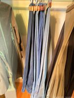 Five pairs of blue denim jeans hanging together, showing color variety