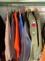 Row of seven windbreaker jackets on closet rod showing colours and styles