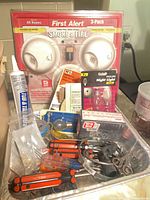 Overview with smoke alarm pack, caulk, Philips night lights, screwdrivers, clamps, hardware