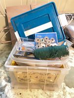 Overall lot stacked: clear organizer, blue box, bobbins pack, green thread spool