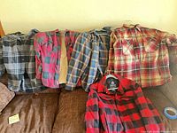 Five plaid flannel jackets displayed on couch