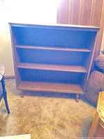 Front view showing three shelves, open back, turned legs