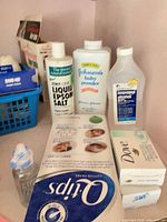 Shelf with liquid Epsom salt, Johnson’s baby powder, isopropyl alcohol, Dove soap pack, Q-tips box and Dr. Brown’s baby bottle