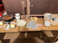 Tabletop with ceramic items, bud vase, urn, bowl, bells, pedestal dish and rocks