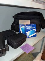 Camera, film box, carrying bag, zip pouches on shelf