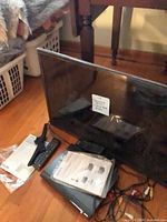 Overall lot showing Samsung TV, stand, remotes, manuals, cables