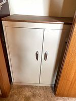 Front view of beige metal cabinet with double doors and wood grain top