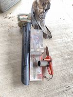Stihl blower-vac, Homelite box, small chainsaw head, blower tube laid on concrete