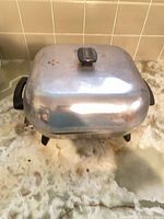 Exterior view of domed aluminum electric roaster with lid and handles