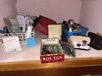 Shelf with Roi-Tan box of grooming tools, toiletry bag, blue basket of toiletries