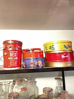 Group of six assorted vintage tins on shelf