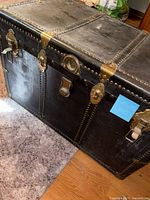Full view of black steamer trunk showing hardware and exterior wear