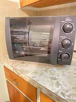 Front view of black Wolfgang Puck Bistro countertop convection toaster oven on counter