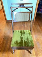 Front view showing green velvet seat, cane backrest, wood frame and hanger rack