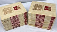Stacked view of all 24 cream hardcover encyclopedia volumes with red and gold titles