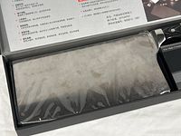 Cleaver inside original box, blade wrapped in protective plastic showing black triple-riveted handle