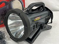 Side view of spotlight showing reflector lens, handle, swivel stand