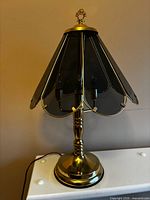 Full view of brass-tone touch lamp with smoked glass shade