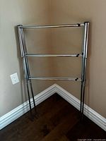 Rack folded flat, lean against wall shows three horizontal bars and four legs