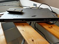 Angled view of DVD player and remote on wooden surface