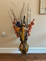 Full view of amber glass vase on metal stand with floral arrangement