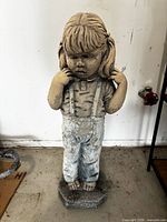 Full view of ceramic garden statue showing girl figure wearing overalls and pigtails on octagonal base