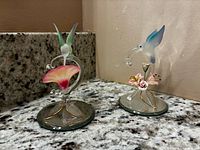 Both glass hummingbird figurines on granite surface