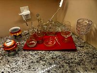 Full group on countertop showing ceramic cream and sugar set, multiple glass cruets, bottle, dish, funnel and stemware