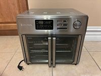 Front view of Kalorik air fryer oven showing digital panel, French doors and accessories inside