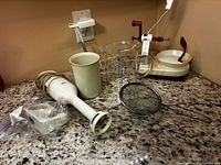 Overall lot view of immersion blender, apple peeler, measuring jug, strainer, blending cup