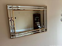 Full view of rectangular gold-tone framed beveled mirror on wall