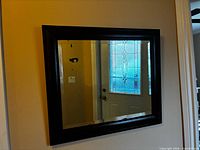 Front view of rectangular mirror with dark wood frame mounted on wall