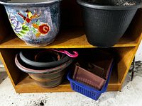 Blue ceramic floral planter and black plastic pot on shelf