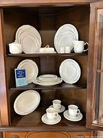 China set displayed in cabinet, showing plates, saucers, cups, platter and serving pieces