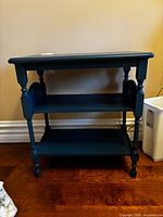 Front view of turquoise wooden side table showing top surface and two shelves