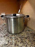 Tall brushed aluminum stock pot with lid on granite countertop