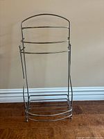 Front view of chrome freestanding towel rack showing towel bars and base shelf