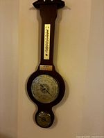Full view of wooden wall barometer hanging on wall