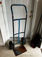 Front view of blue metal hand truck showing frame, wheels and toe plate