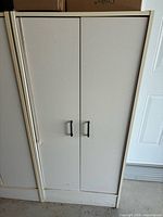 Cabinet front view with closed double doors and black pulls