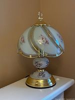 Full view of small white floral touch lamp on surface