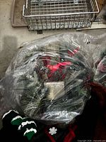 Plastic-wrapped artificial wreath with pinecones, red bows and greenery
