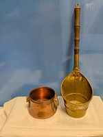 Brass dipper and copper pot side by side