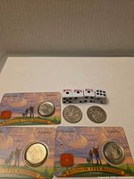 Overall lot showing two Millennium quarter cards, two 50-cent coins, four Bicycle dice
