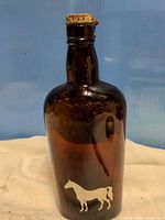 Front view showing amber glass bottle and white horse graphic