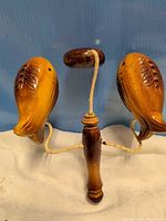 Full view of wooden fish percussion clapper showing handle, two fish blocks, and suspended striker