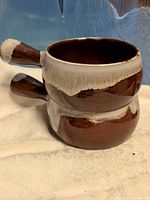 Two stacked brown drip-glaze soup bowls showing full exterior and handles